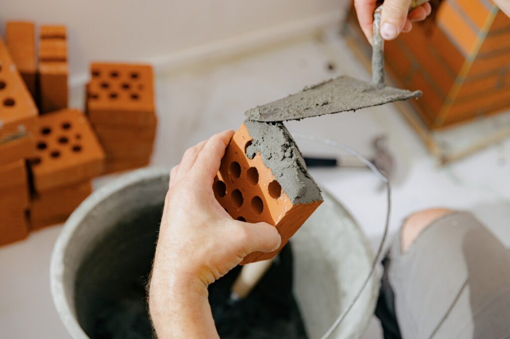 A young man makes brickwork on the chimney of a fireplace.