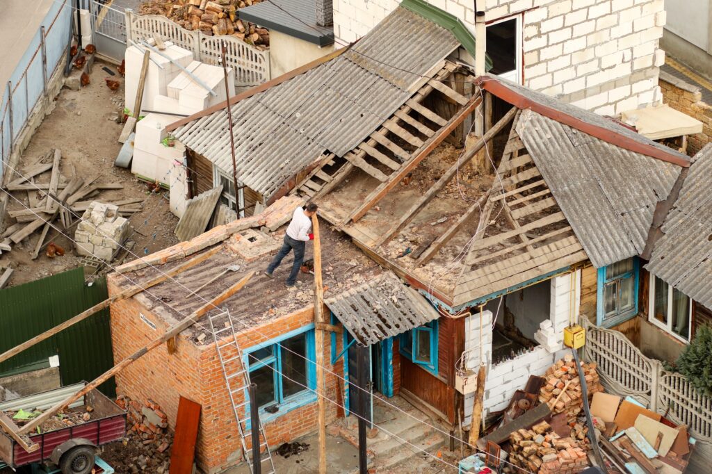 An old, dilapidated house with a worn-out wooden roof, showing signs of renovation