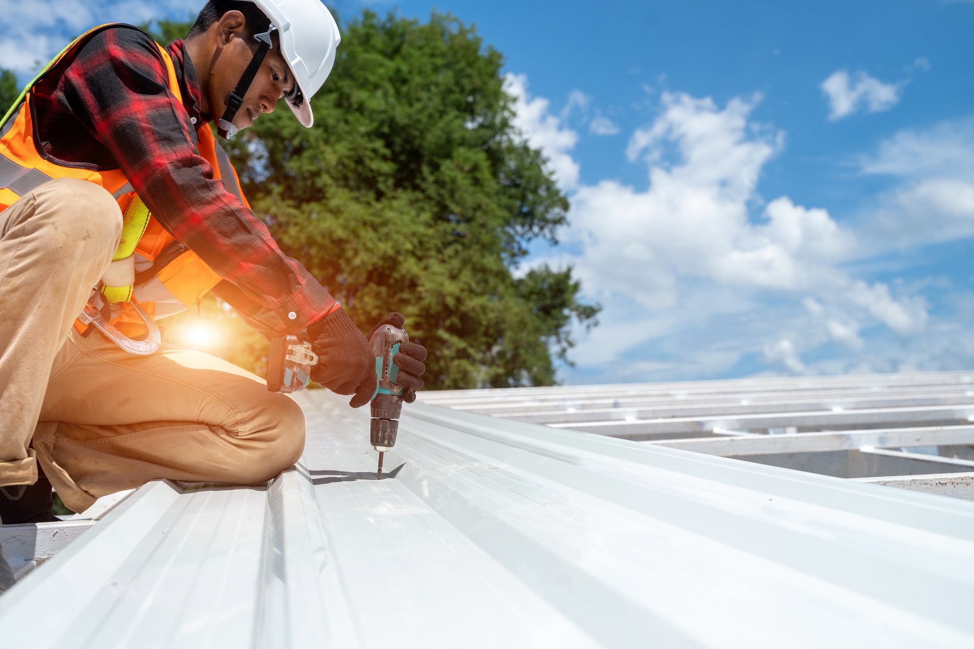 Roofer working at metal profile roof installation,Roofing tools,Electric drill used on new roofs.